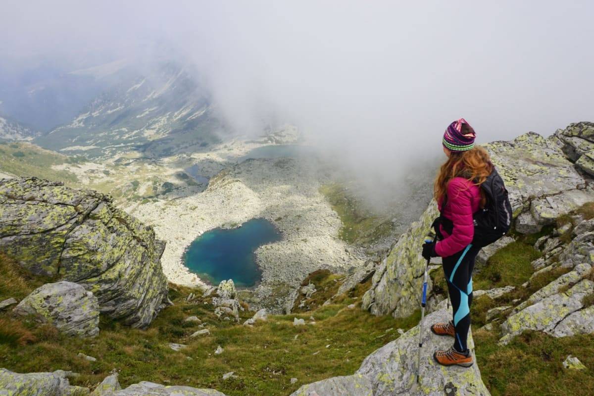 Femeie care sta pe o stanca si admira privelistea Muntilor Parang