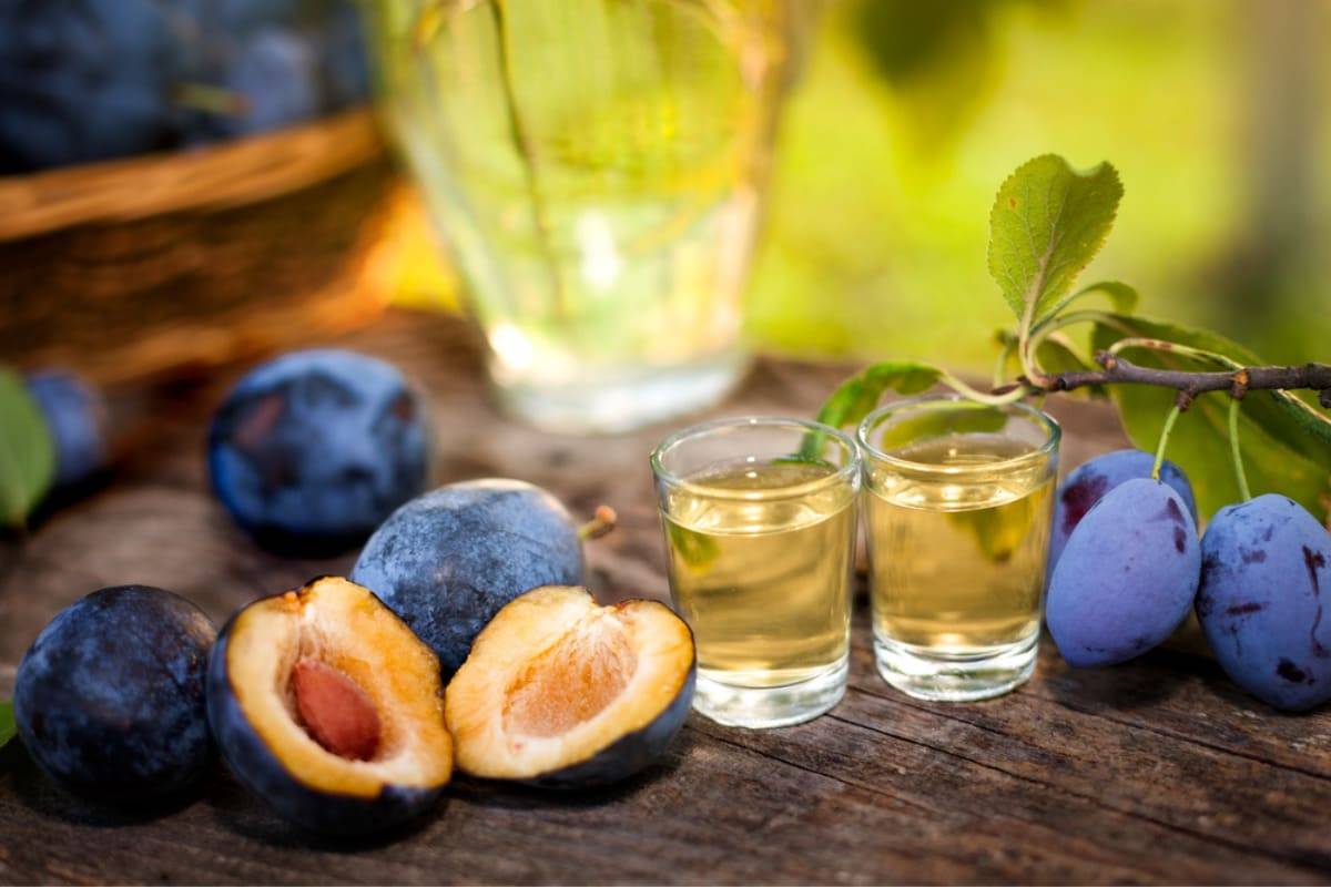 Pahare cu palinca pe masa rustica cu prune
