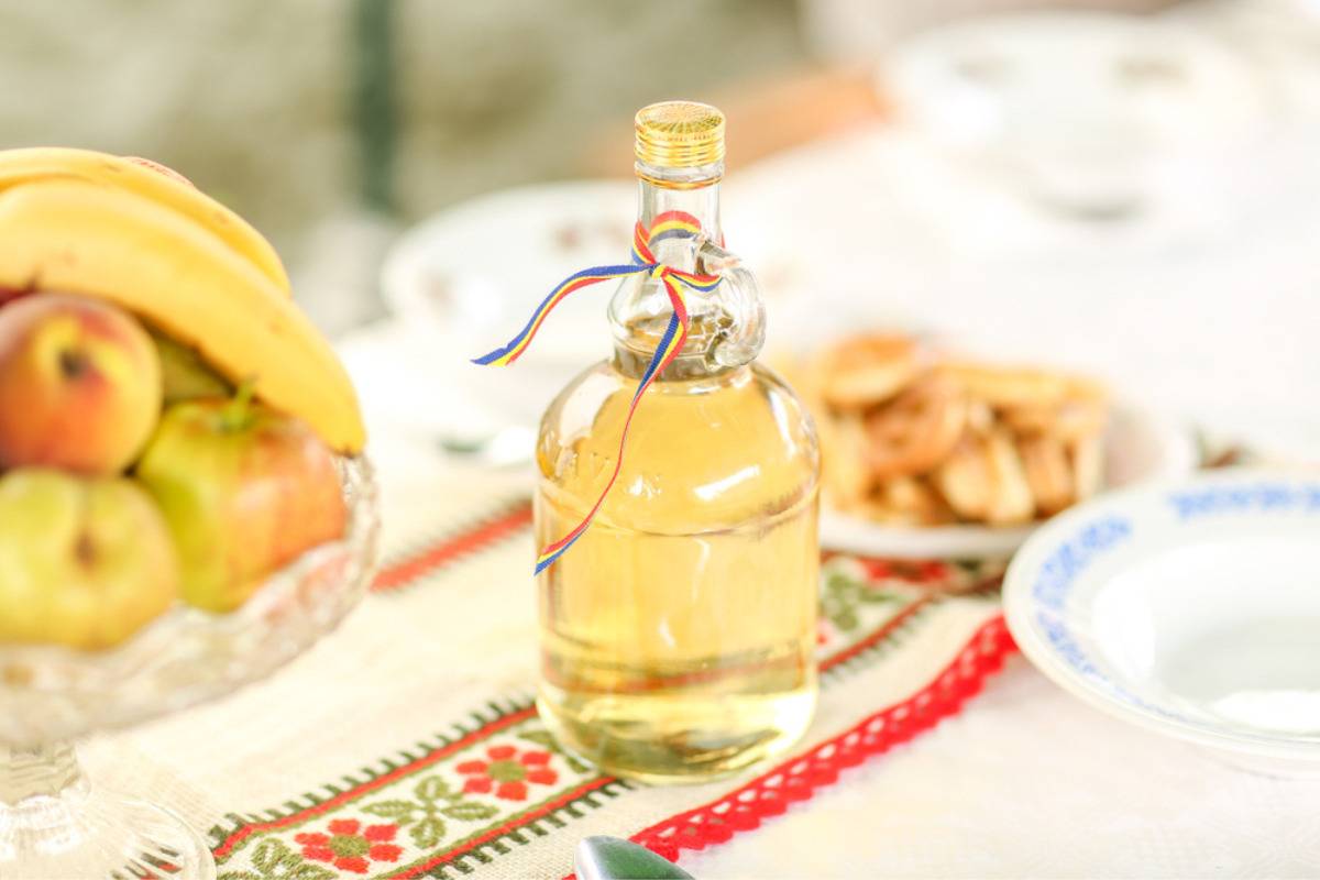 Sticla cu palinca romaneasca pe masa rustica traditionala